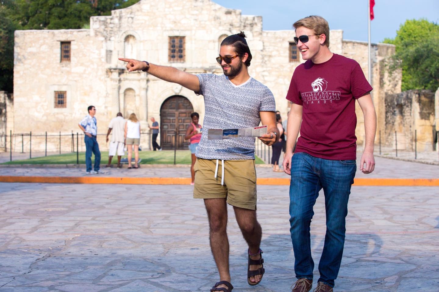 two students walk by The Alamo